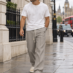 Man wearing the light grey drawstring tailored trousers while walking in London