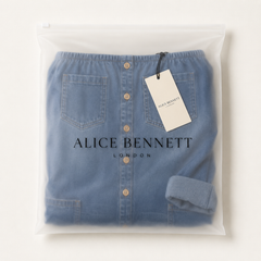 Zaria blue denim jumpsuit in a semi-transparent Alice Bennett London zip bag with branded hangtag